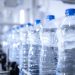 Close up view on plastic bottles of water in bottling factory being transported by conveyor belt automated machine.