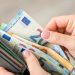 Close up of female hands holding grey wallet with 20 and 50 euro banknotes