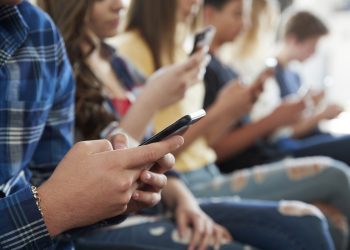 Close Up Of A Line Of High School Students Using Mobile Phones